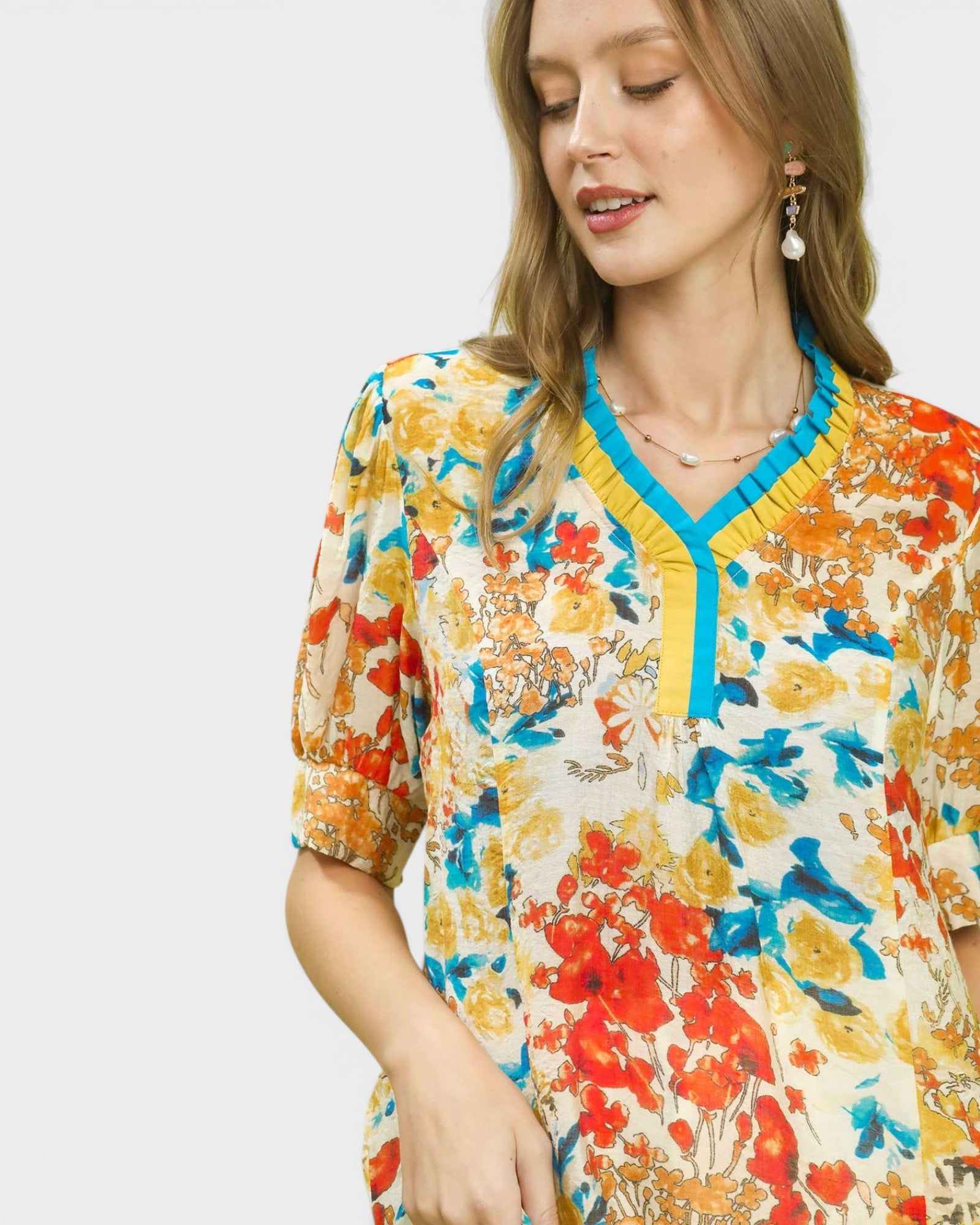 Woman wearing a colorful floral dress with a blue trim on a white background