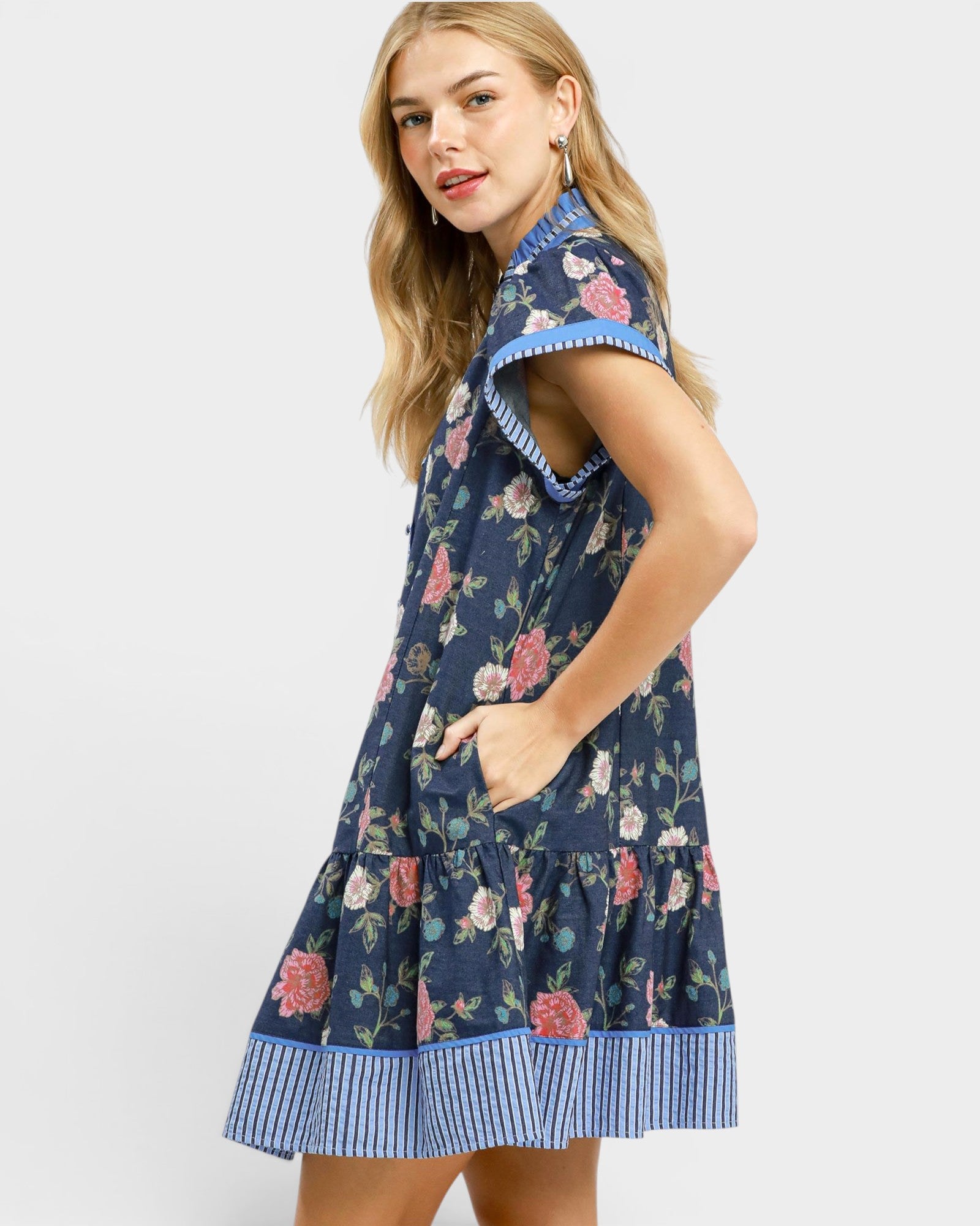 Woman wearing a navy floral dress with blue trim on a white background
