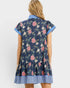 Woman wearing a navy floral dress with blue trim on a white background