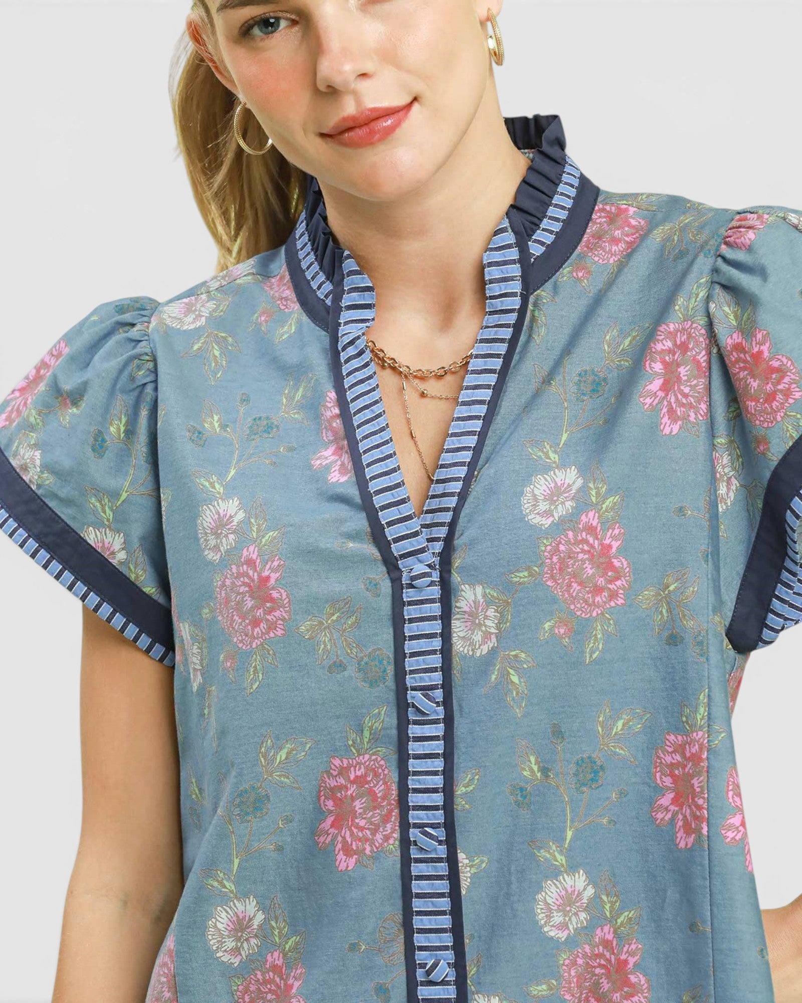 Woman wearing a floral dress with blue trim on a white background