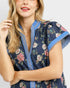 Woman wearing a navy floral dress with blue trim on a white background