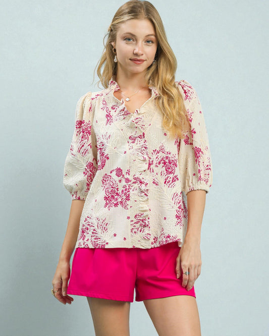Woman wearing a floral blouse and pink shorts against a light gray background