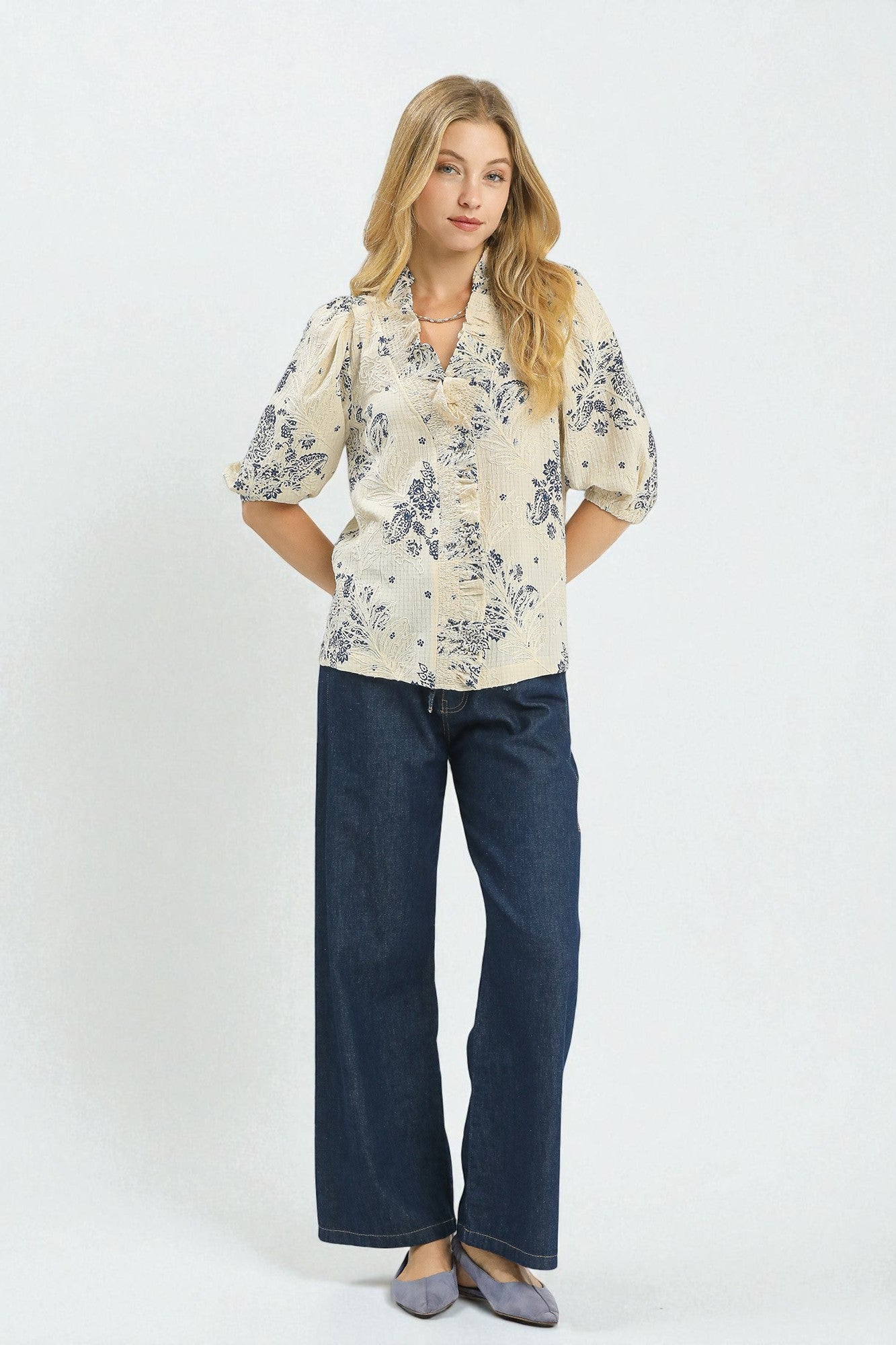 Woman wearing a floral blouse and blue jeans on a white background