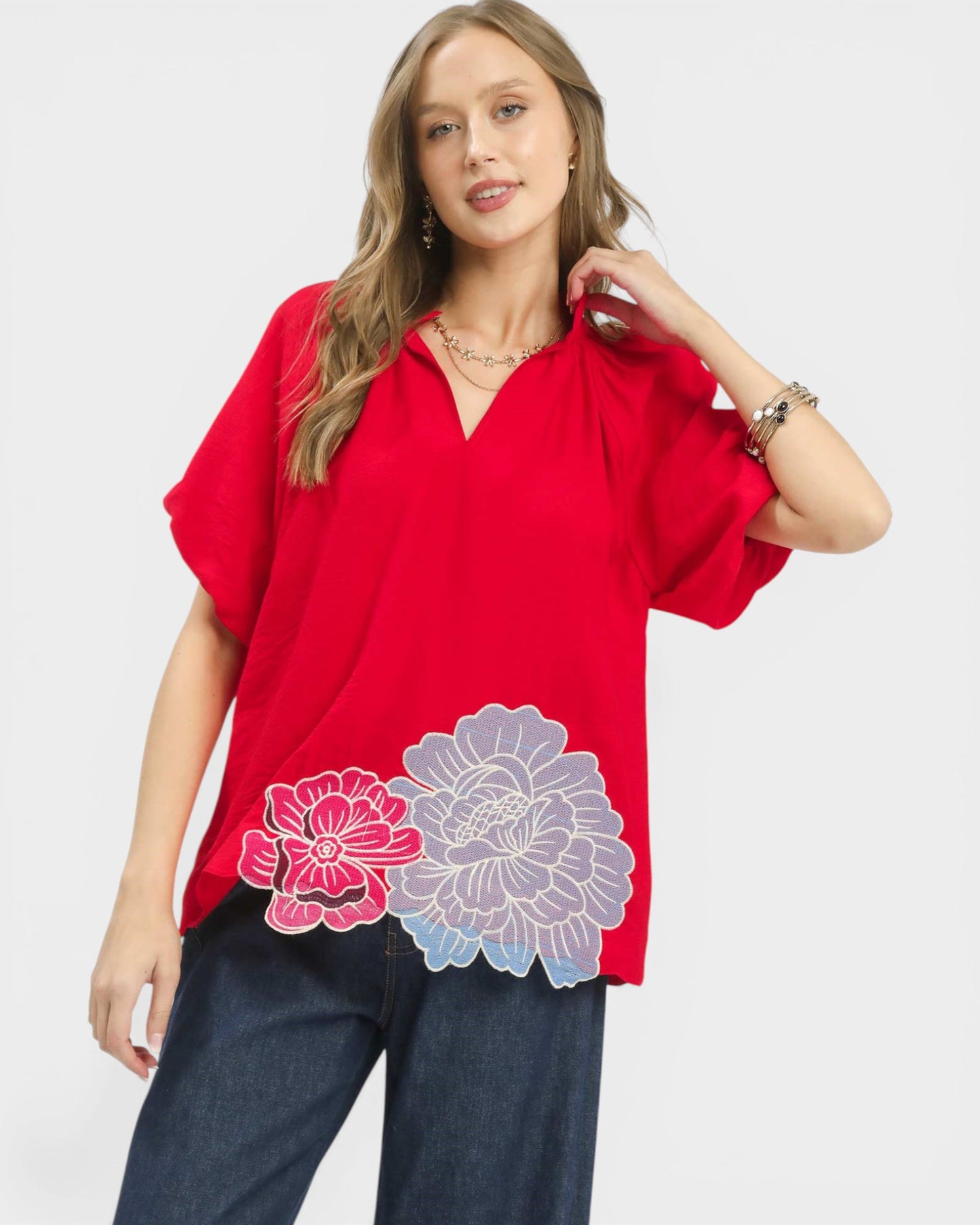 Woman wearing a red blouse with floral designs on a white background