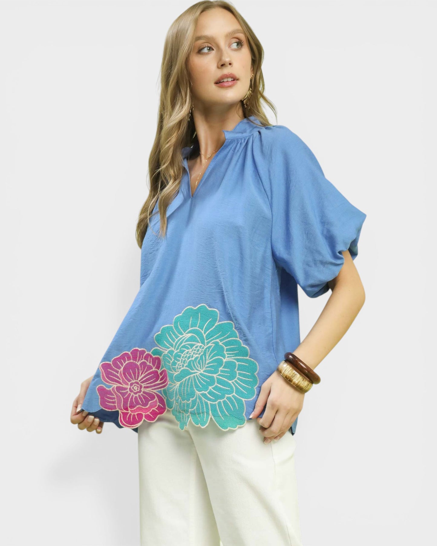 Woman wearing a blue top with floral designs on a white background