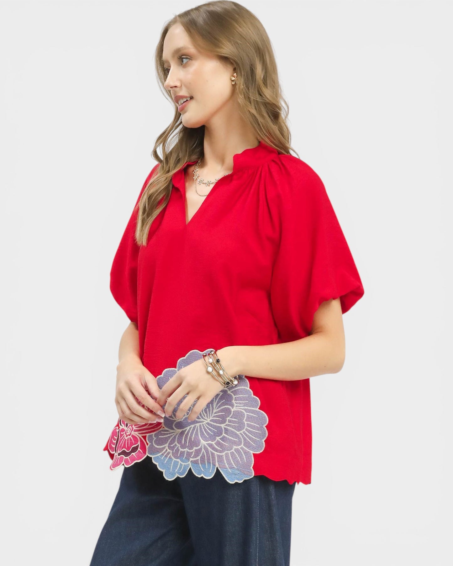 Woman wearing a red blouse with floral details on a white background