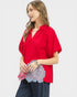 Woman wearing a red blouse with floral details on a white background