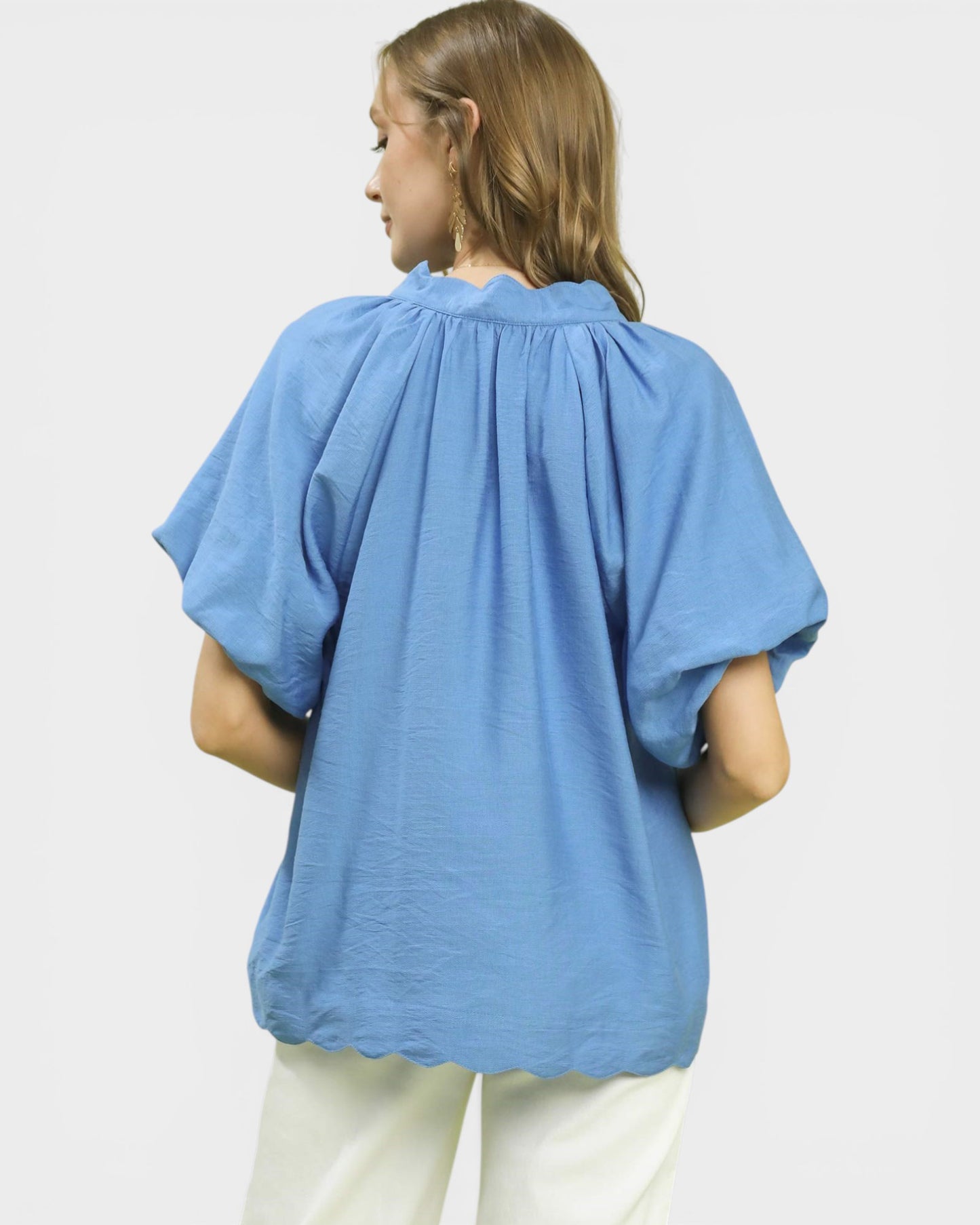 Person wearing a blue blouse with short sleeves on a white background