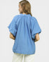 Person wearing a blue blouse with short sleeves on a white background