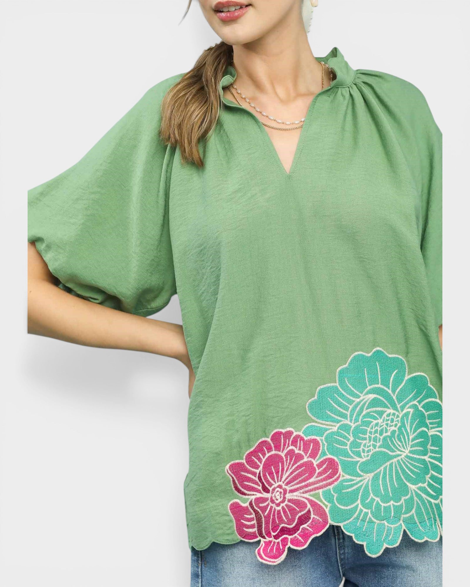 Green blouse with floral designs on a white background