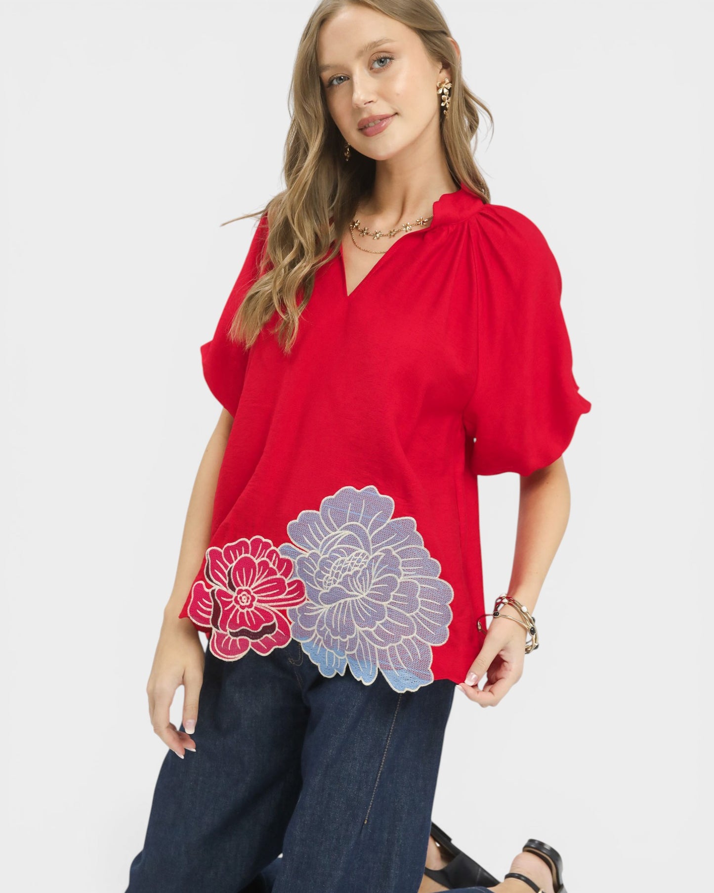 Woman wearing a red blouse with floral designs on a white background