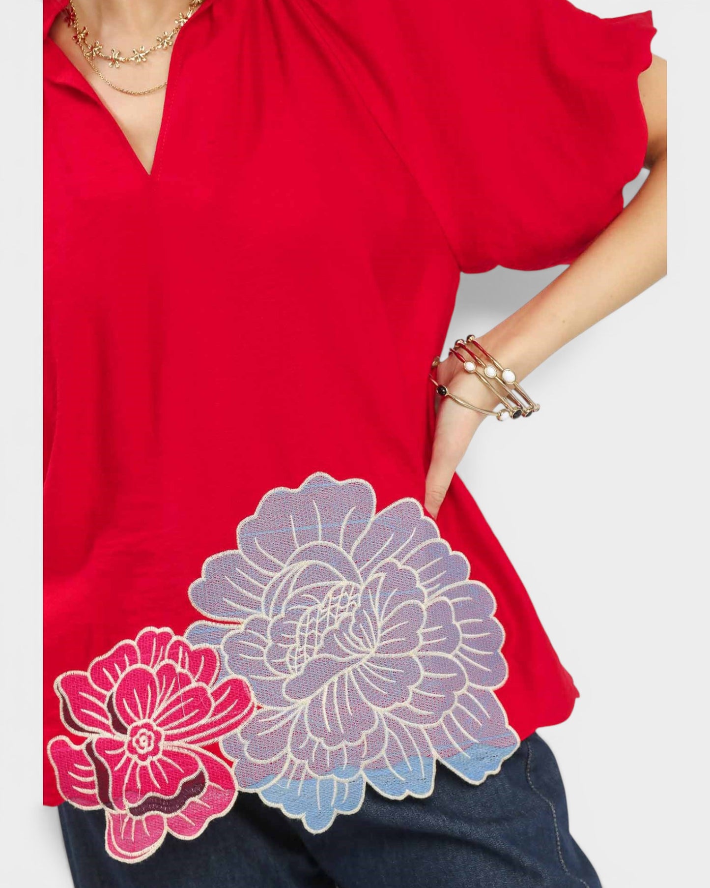 Red top with floral designs on a plain background