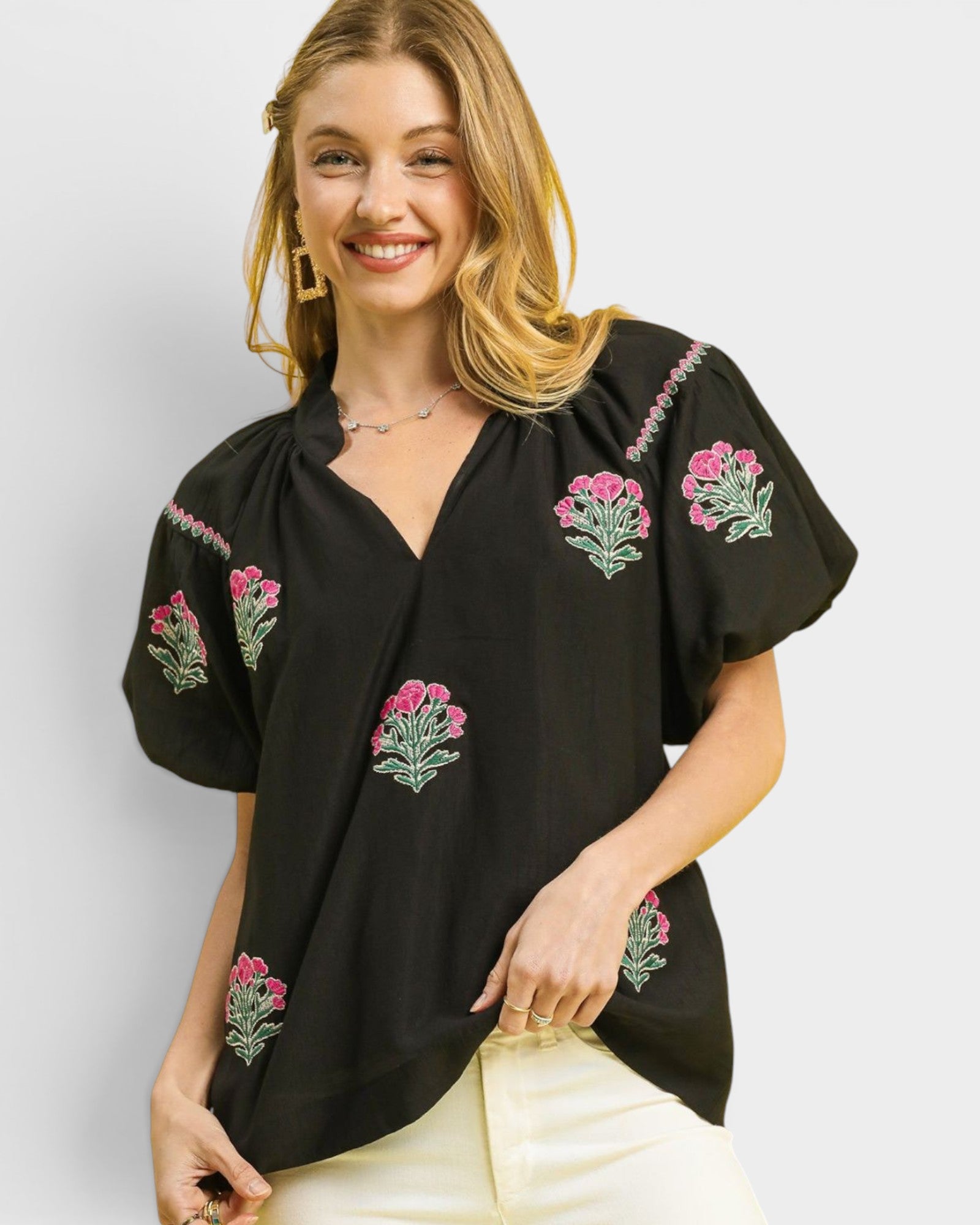 Woman wearing a black blouse with floral embroidery on a white background