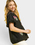 Woman wearing a black top with floral embroidery on a white background