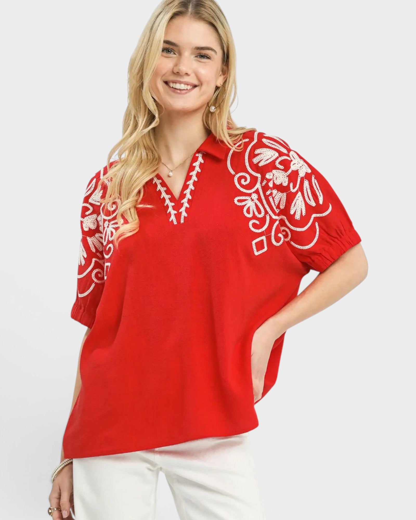 Woman wearing a red blouse with white embroidery on a white background