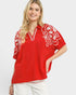Woman wearing a red blouse with white embroidery on a white background