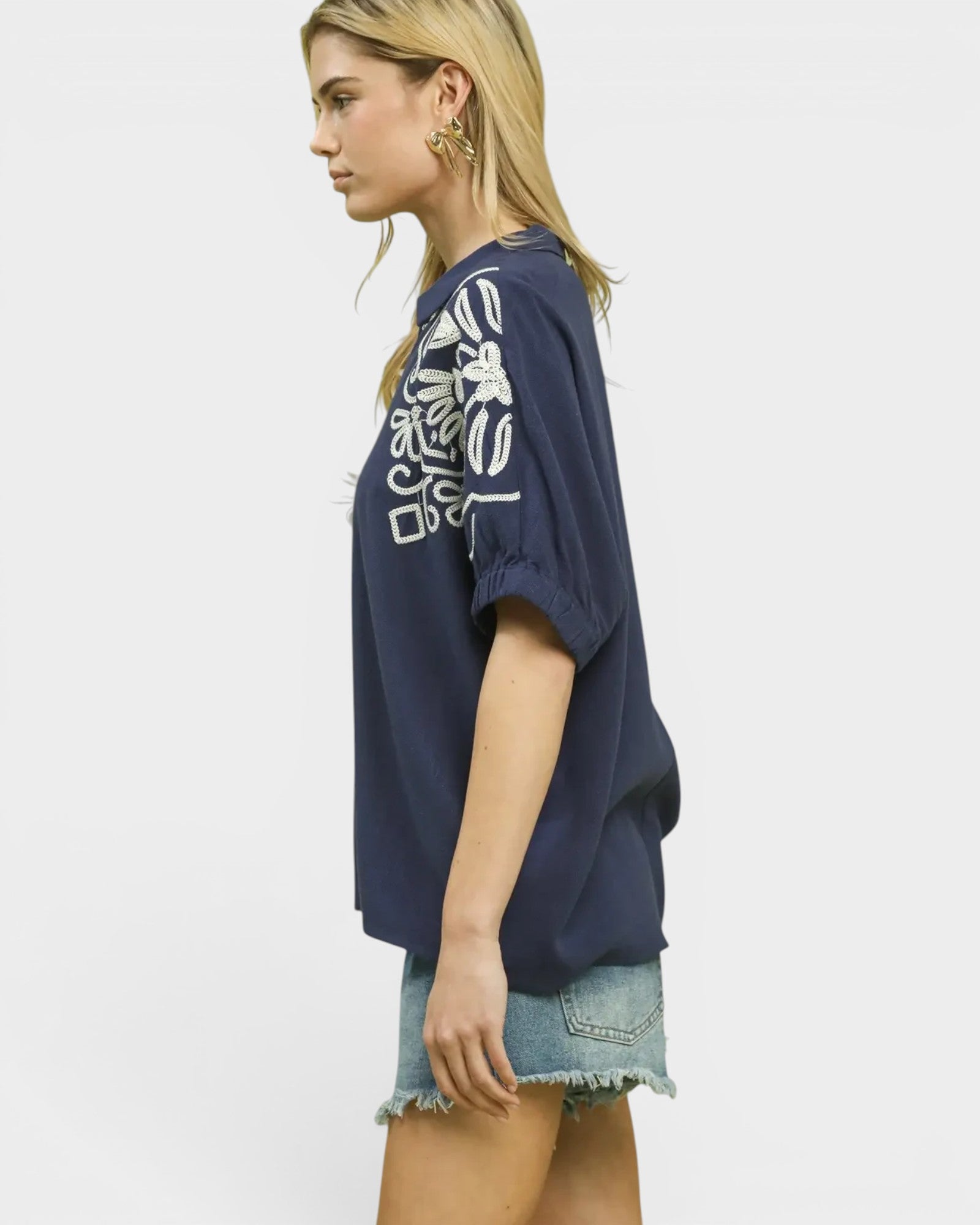 Woman wearing a navy blue t-shirt with a white graphic design on a plain background