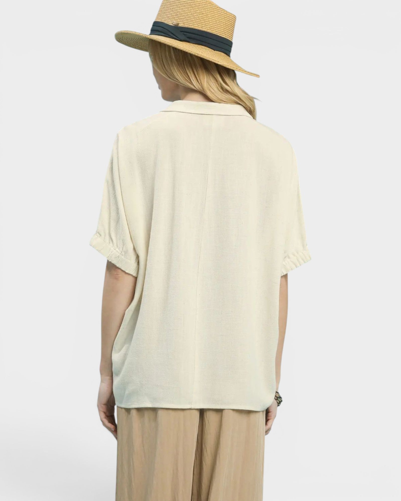 Person wearing a light-colored shirt and beige pants with a straw hat on a white background