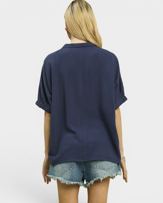 Person wearing a navy blue shirt and denim shorts on a white background