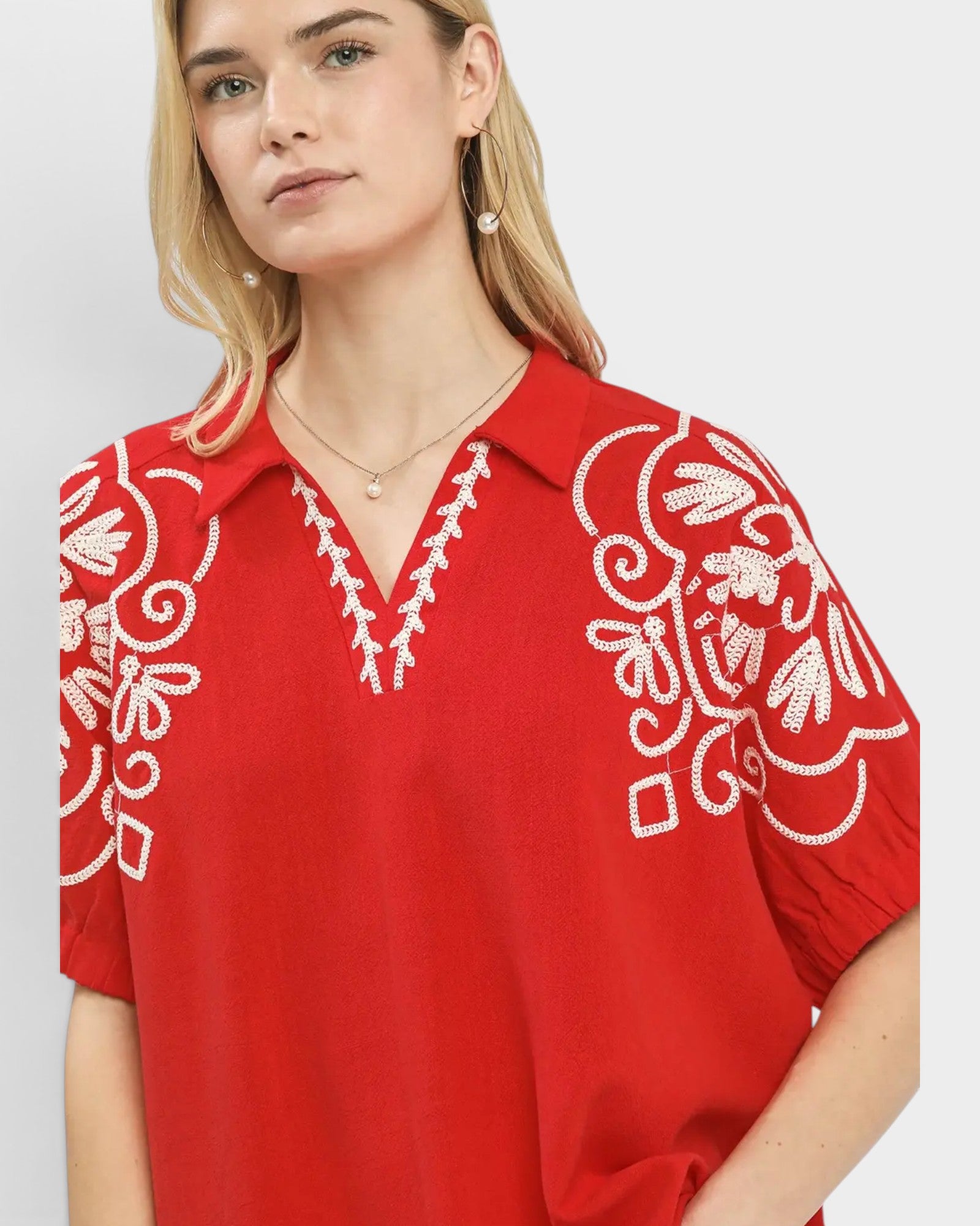 Red blouse with white embroidery on a plain background