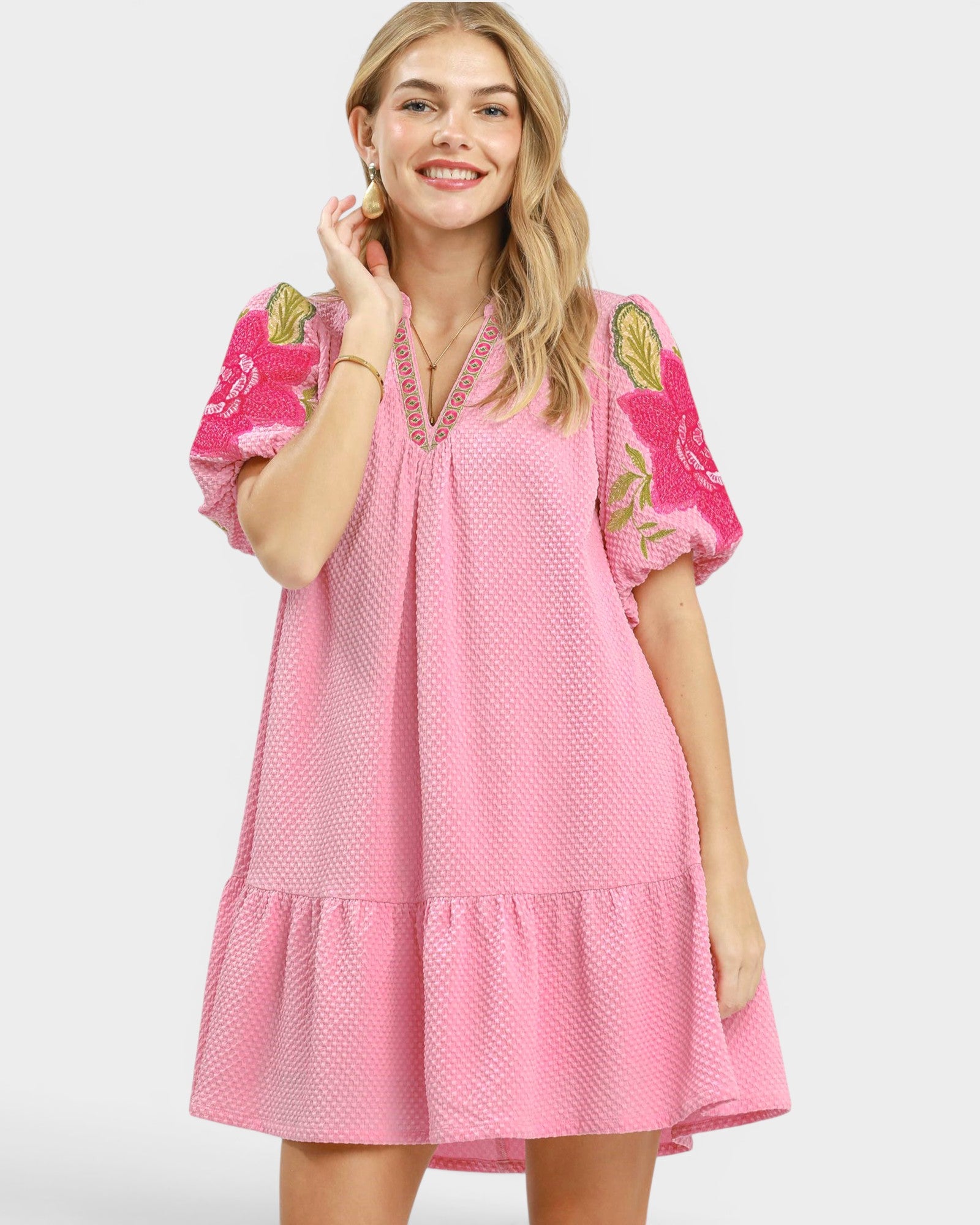 Woman wearing a pink dress with floral sleeves on a white background