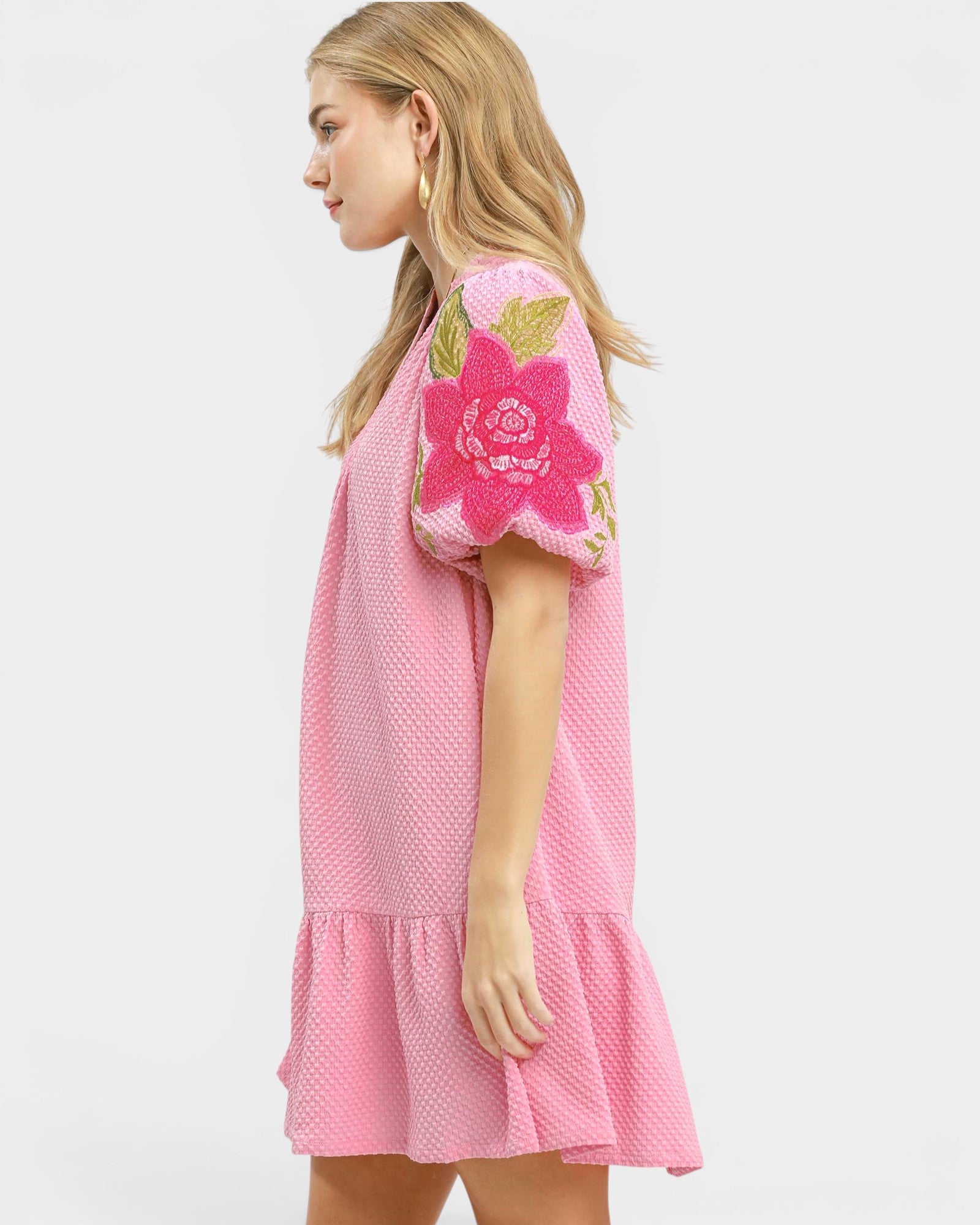 Pink dress with floral embroidery on a white background
