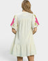 Woman wearing a cream-colored dress with pink floral sleeves on a white background