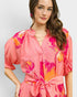 Woman wearing a pink floral dress against a plain background