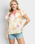 Woman wearing a floral blouse with pink accents and denim shorts on a light gray background