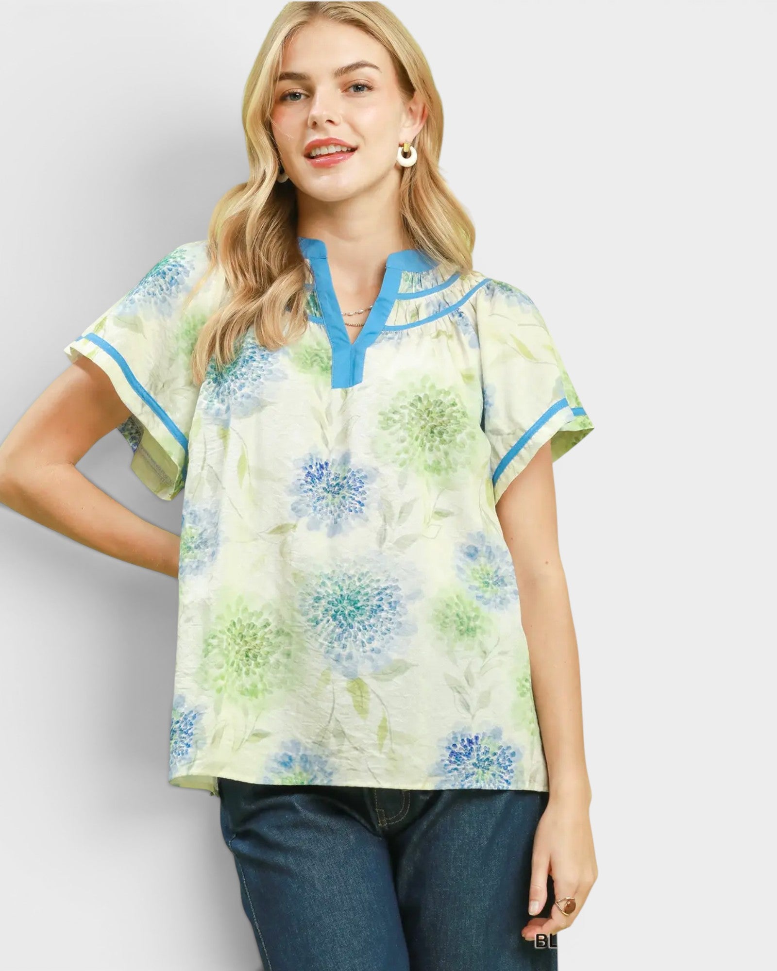 Woman wearing a floral blouse with blue accents on a plain background