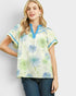Woman wearing a floral blouse with blue accents on a plain background