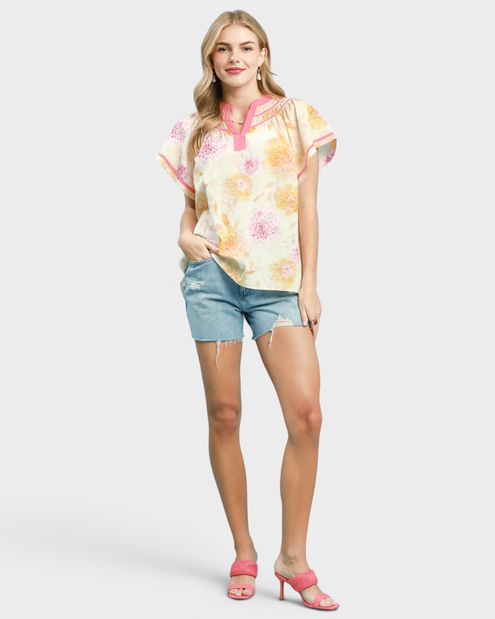 Woman wearing a floral blouse and denim shorts on a white background