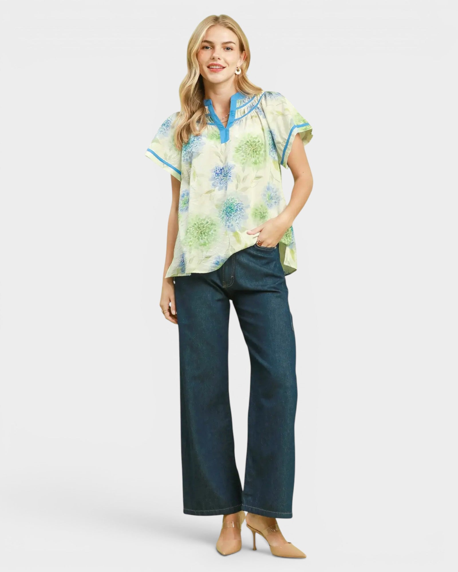 Woman wearing a floral blouse and blue jeans on a white background