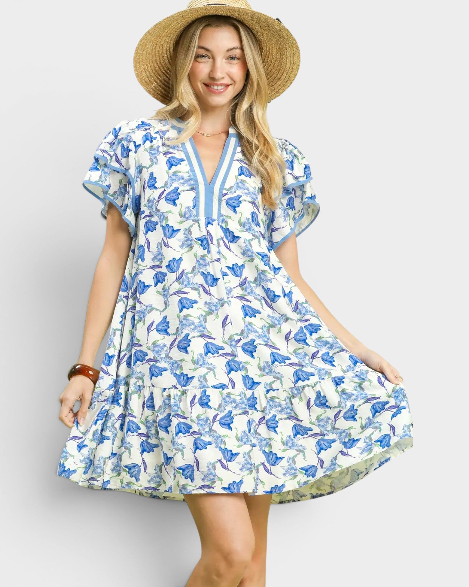 Woman wearing a blue floral dress and straw hat on a white background