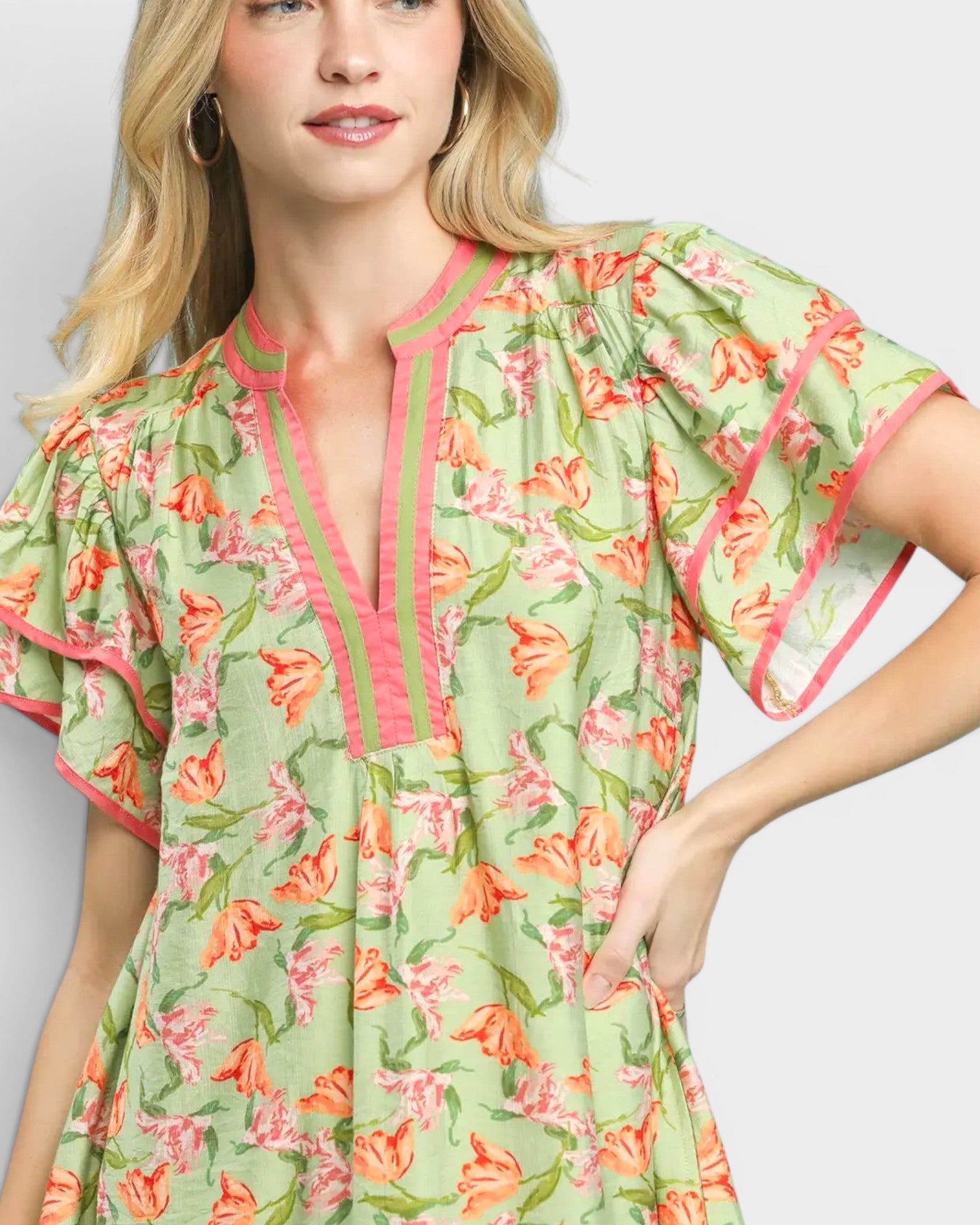 Woman wearing a floral dress with green, orange, and pink colors on a white background