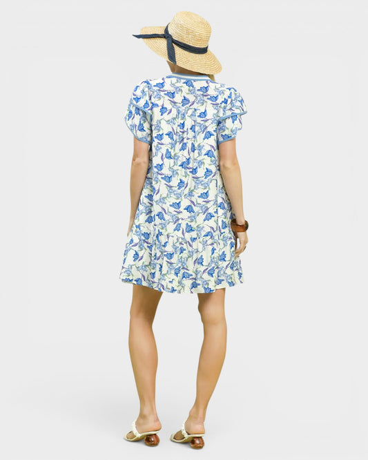 Woman wearing a blue floral dress and straw hat on a white background