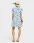 Woman wearing a blue floral dress and straw hat on a white background