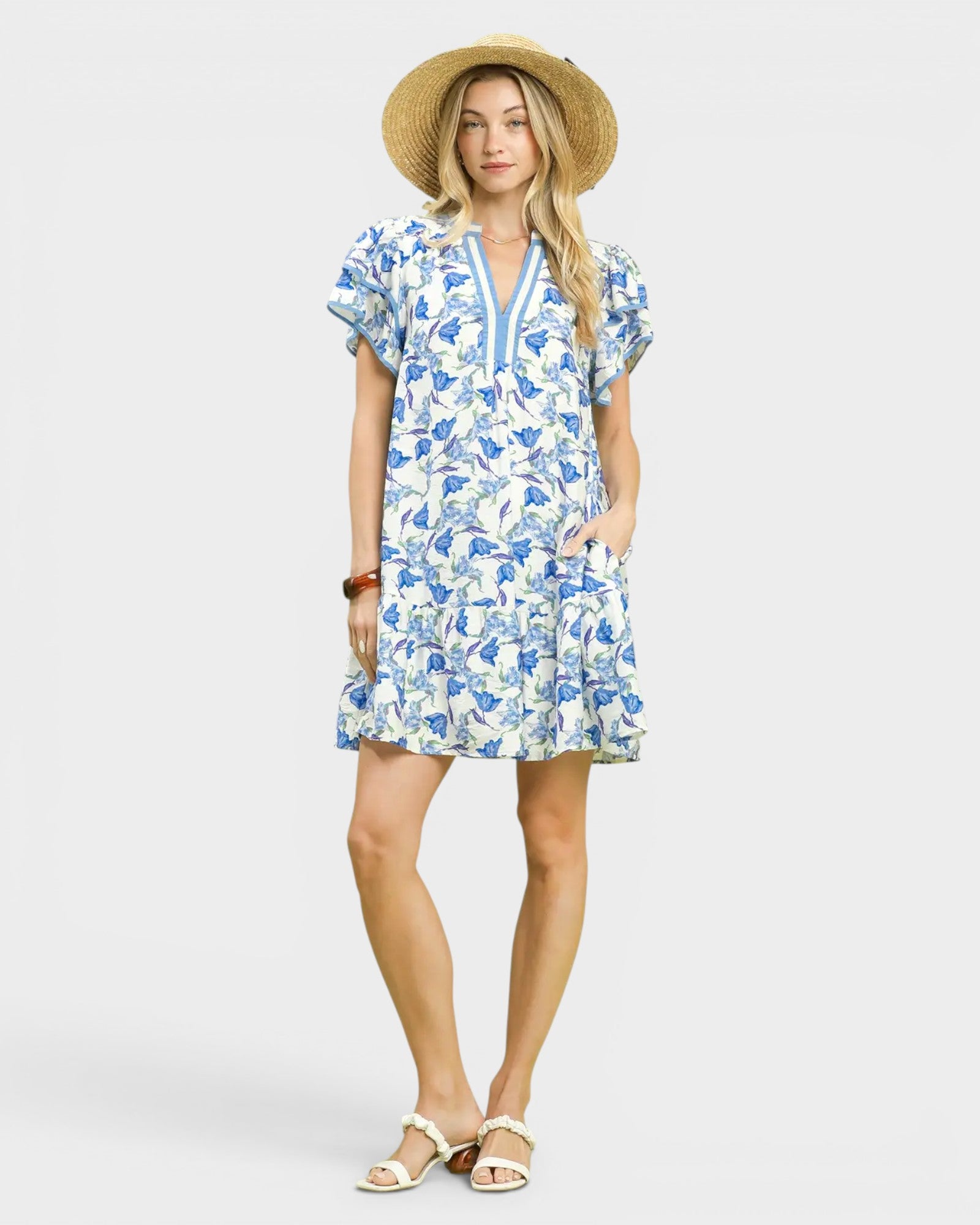 Woman wearing a blue floral dress and straw hat on a white background