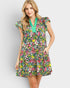 Woman wearing a colorful floral dress with a green neckline on a light gray background