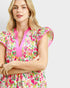Woman wearing a colorful floral dress with pink accents on a white background
