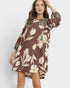 Woman wearing a brown floral dress with checkered sleeves on a white background