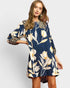 Woman wearing a navy floral dress with a plain background