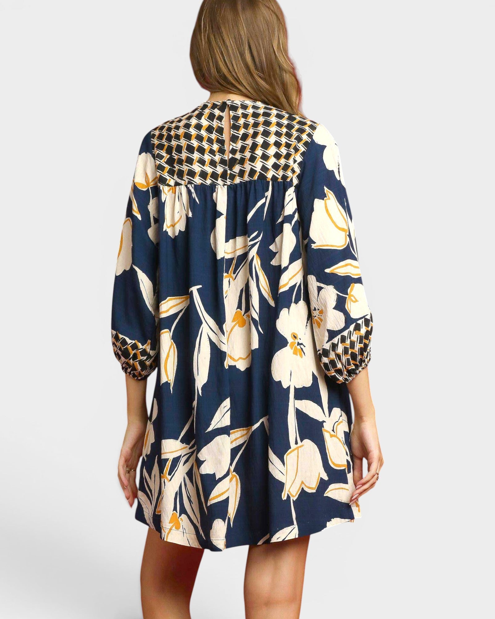 Woman wearing a navy floral dress with leopard print accents on a white background