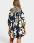Woman wearing a navy floral dress with leopard print accents on a white background