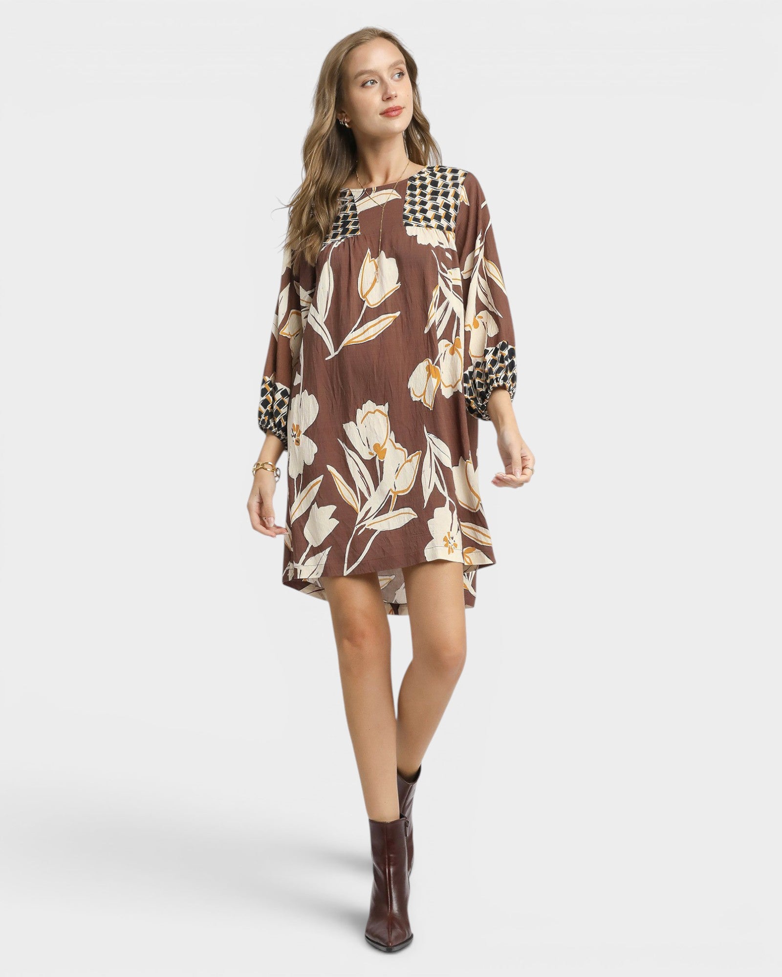 Woman wearing a brown floral dress with a plain background