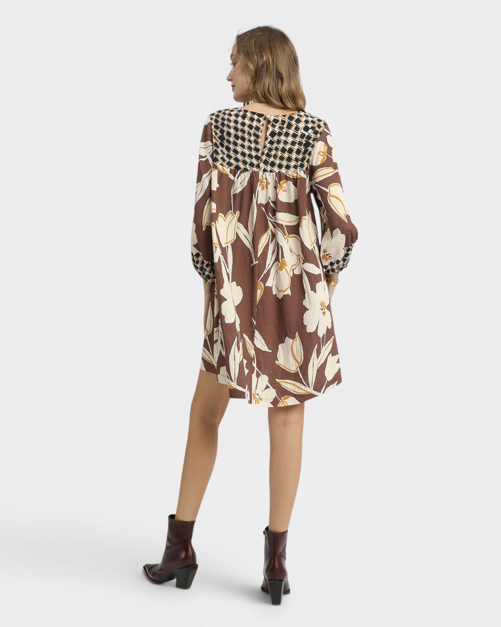 Woman wearing a brown floral dress with a checkered hood on a white background