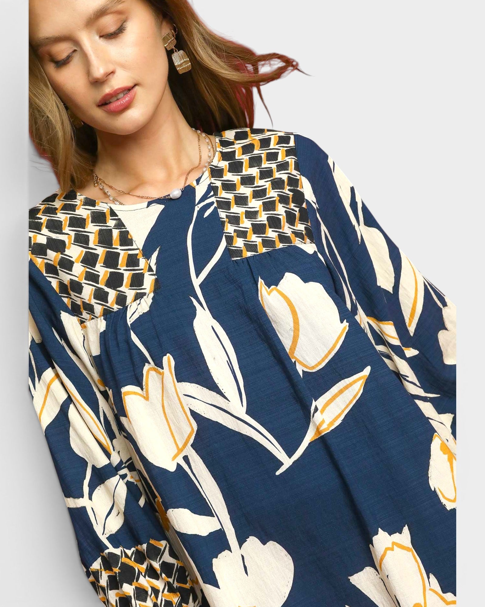 Woman wearing a patterned dress with floral design on a plain background