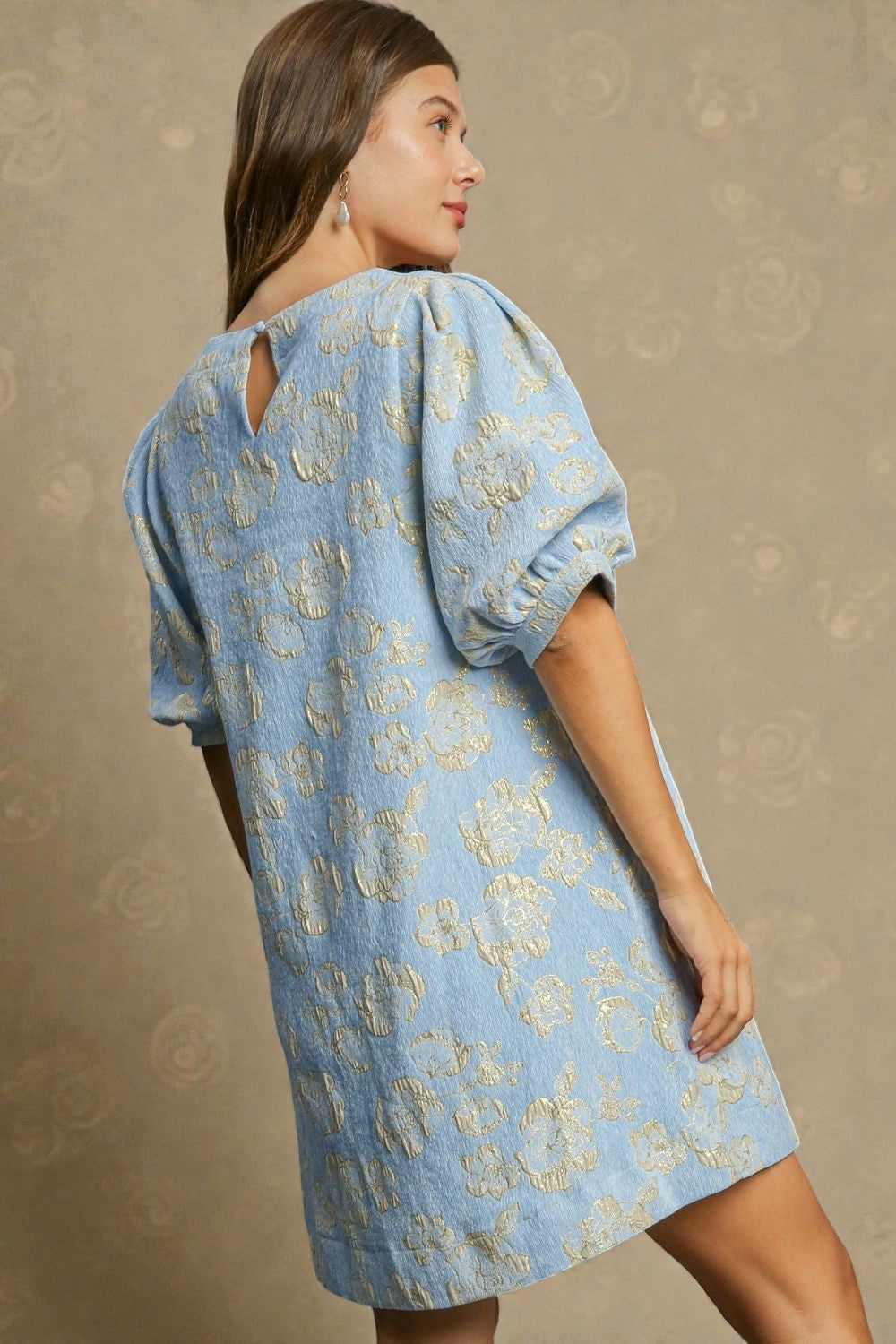 Woman wearing a blue floral dress against a beige background