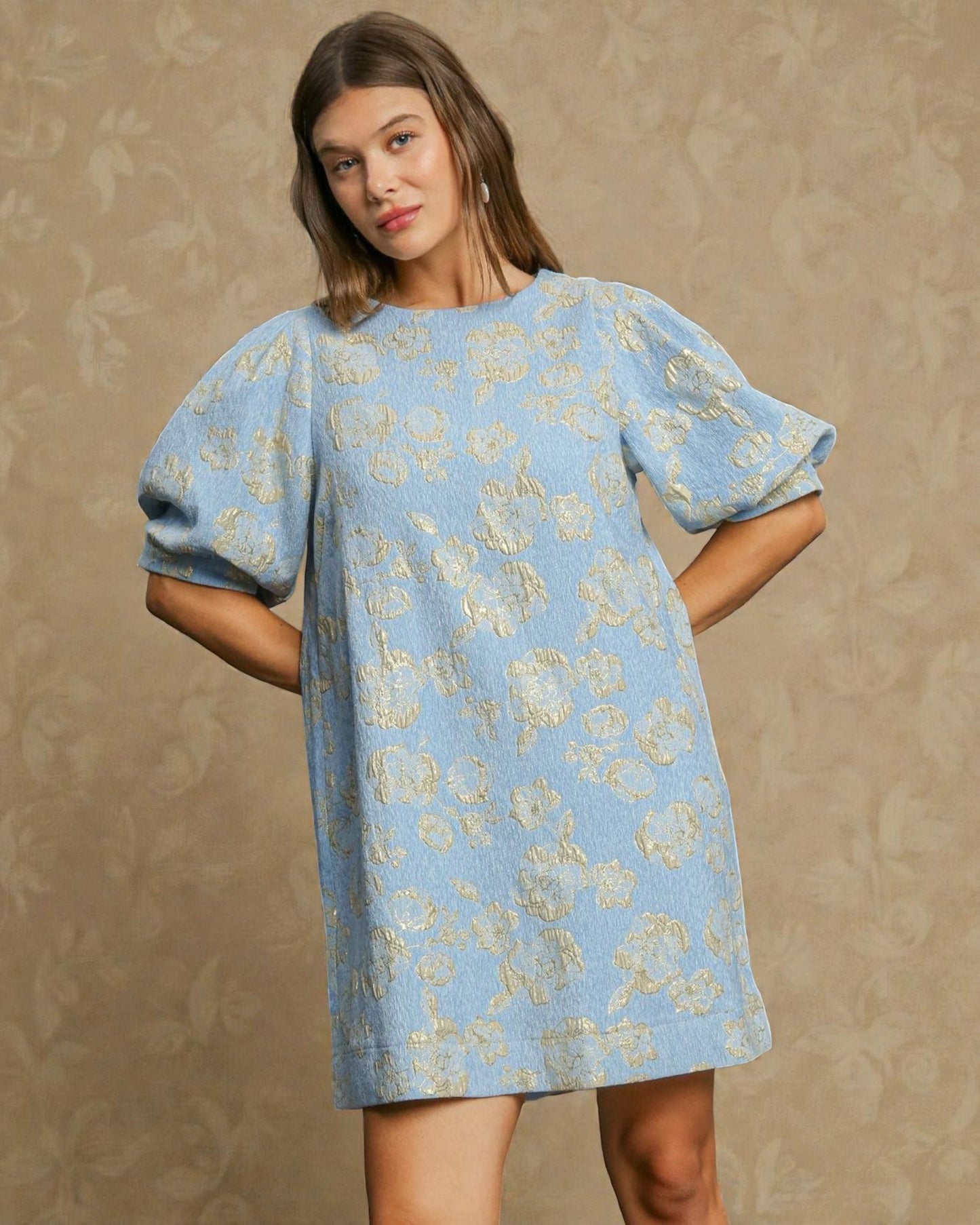 Woman wearing a blue floral dress against a beige background