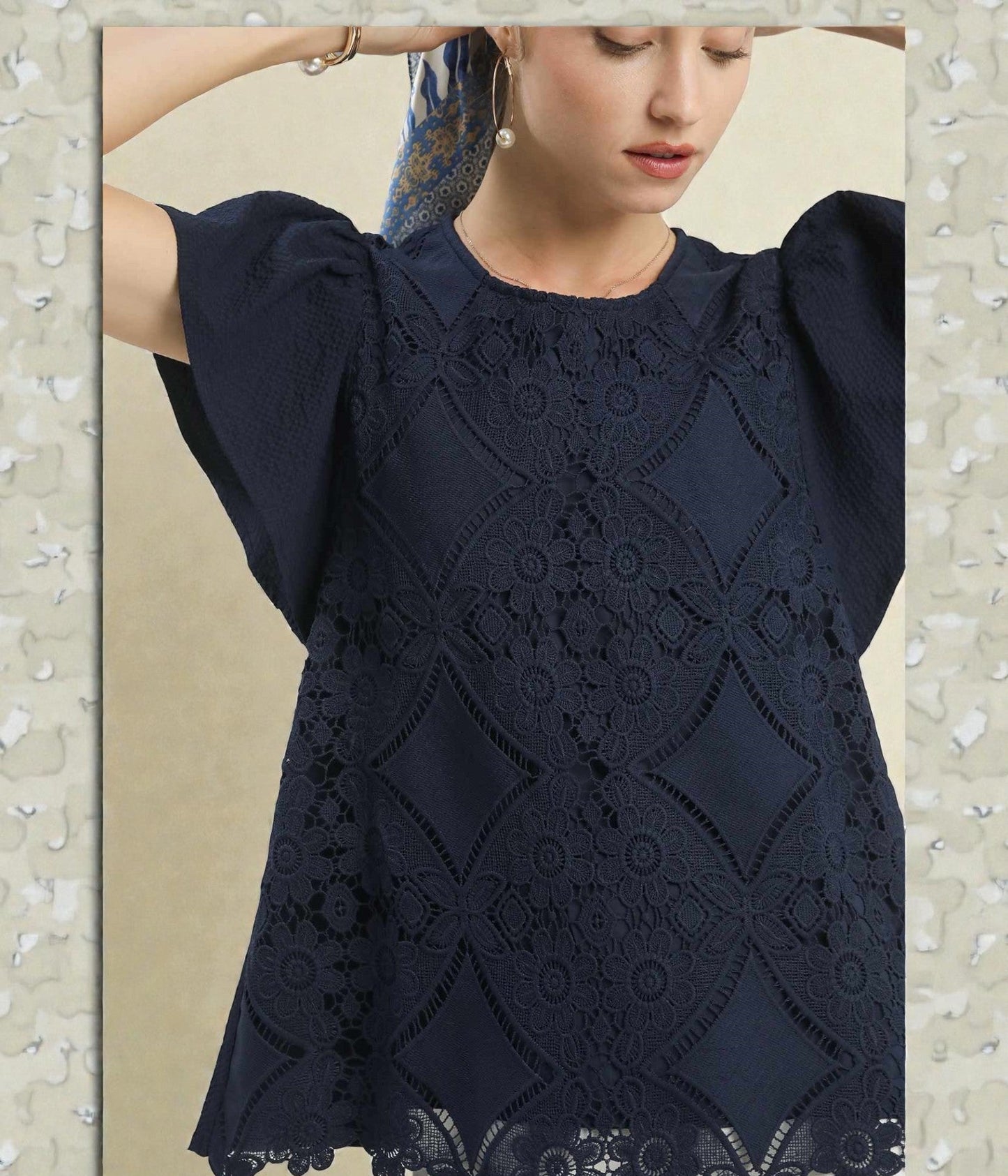 Navy blue lace top worn by a model on a neutral background